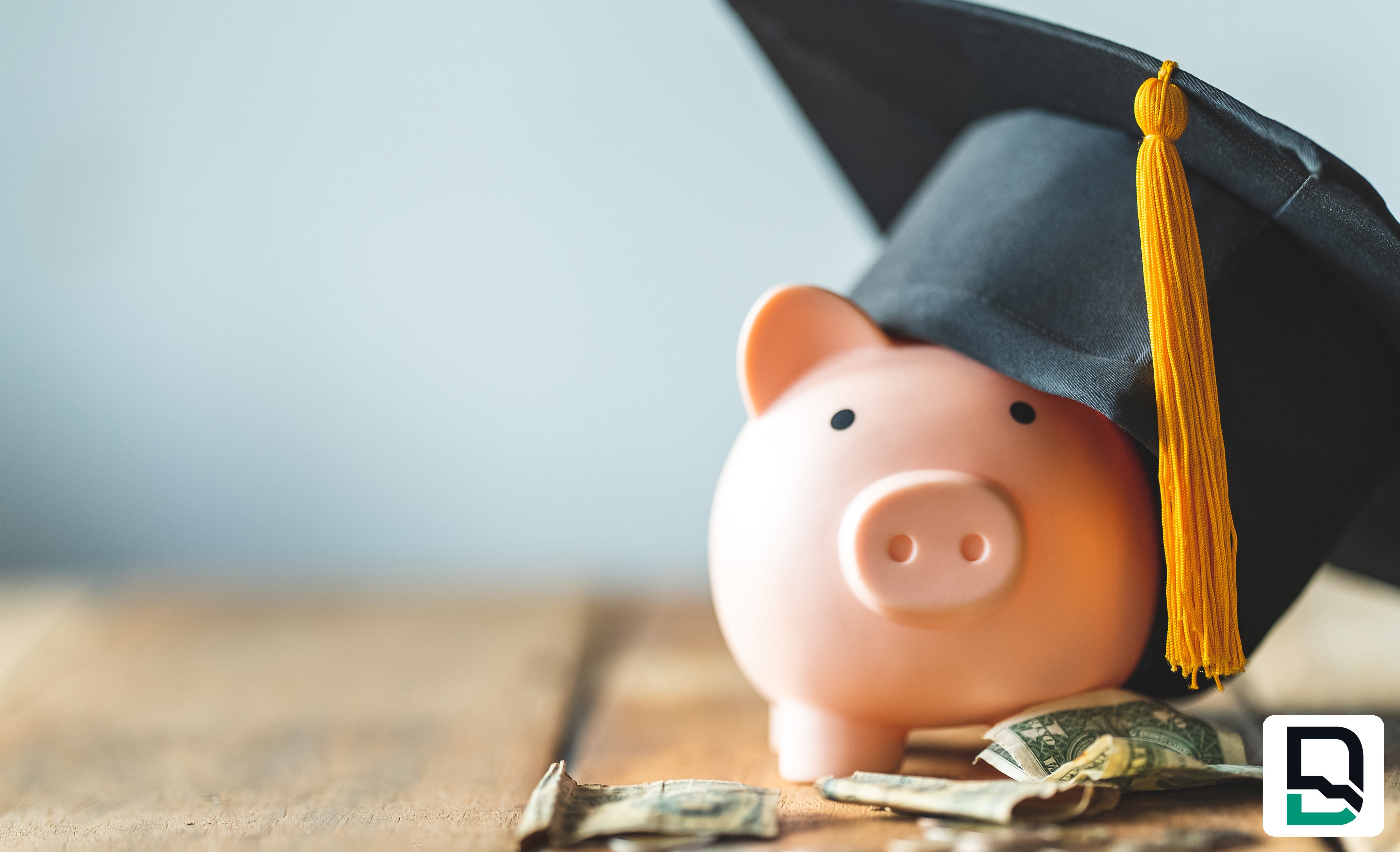 Piggy bank wearing graduation hat sitting on random coins and dollar bills