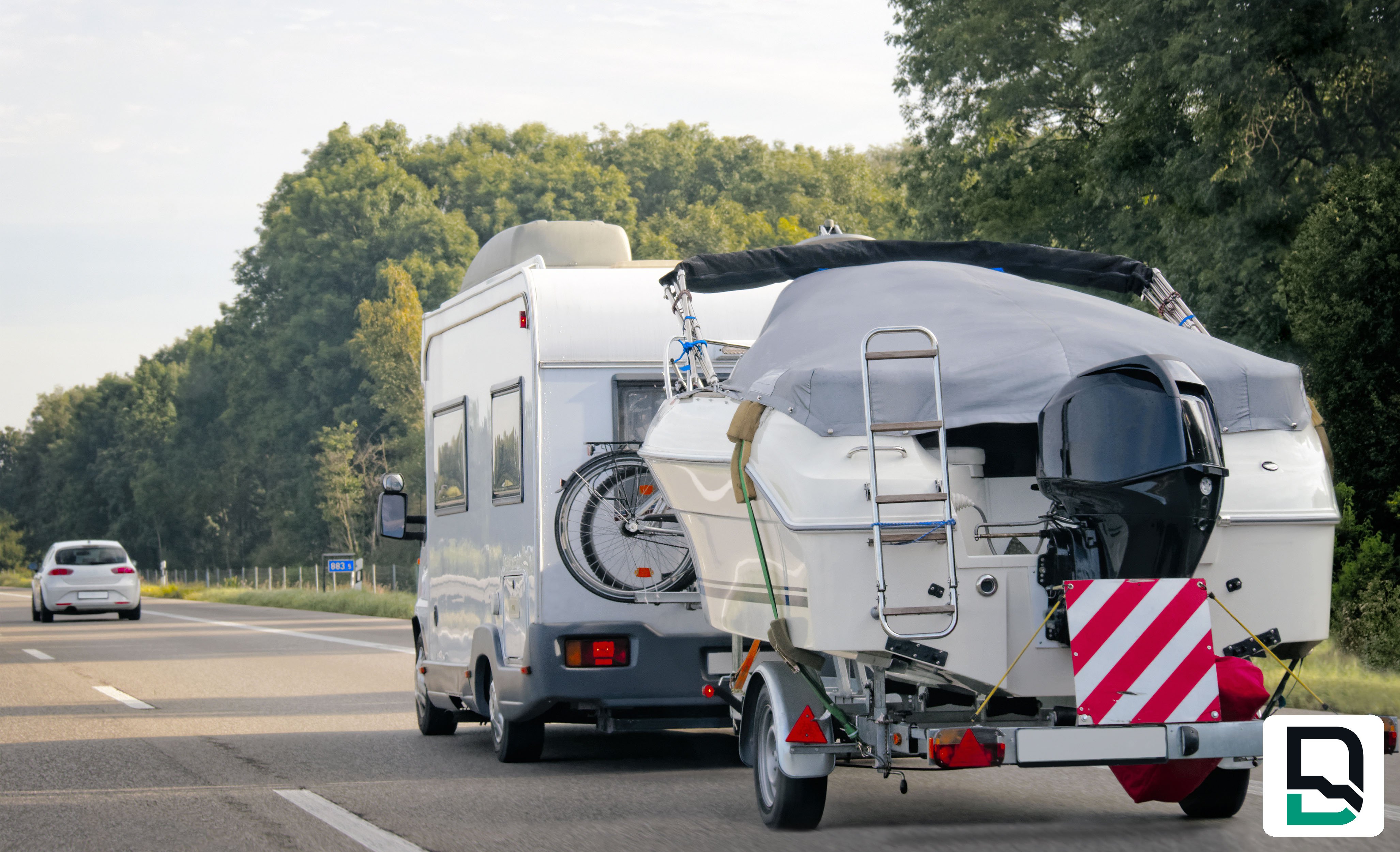 Camper pulling book on highway lined in trees