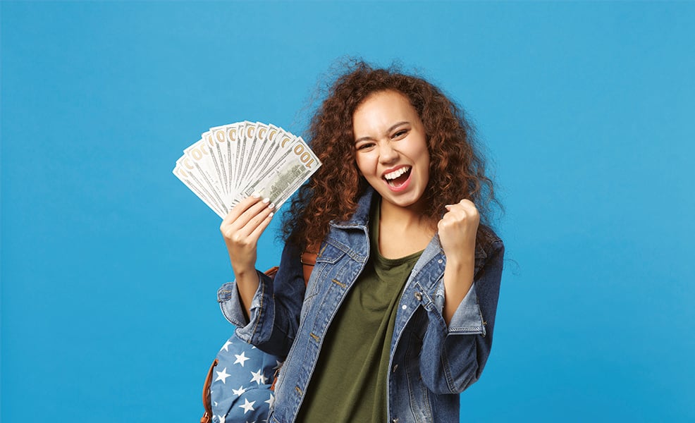 Teen girl holding $100 bills against blue background