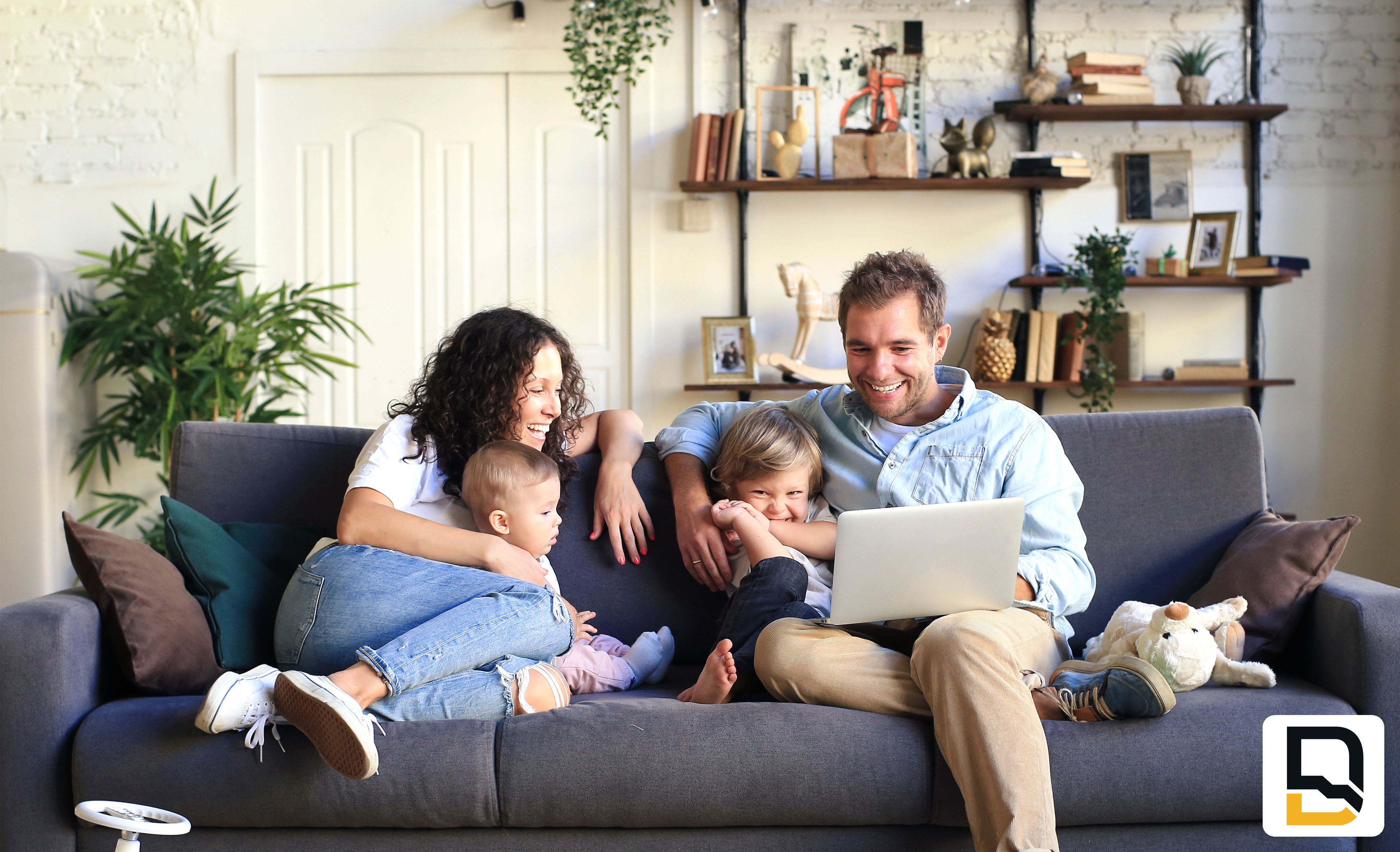 Happy family sitting on couch looking at laptop