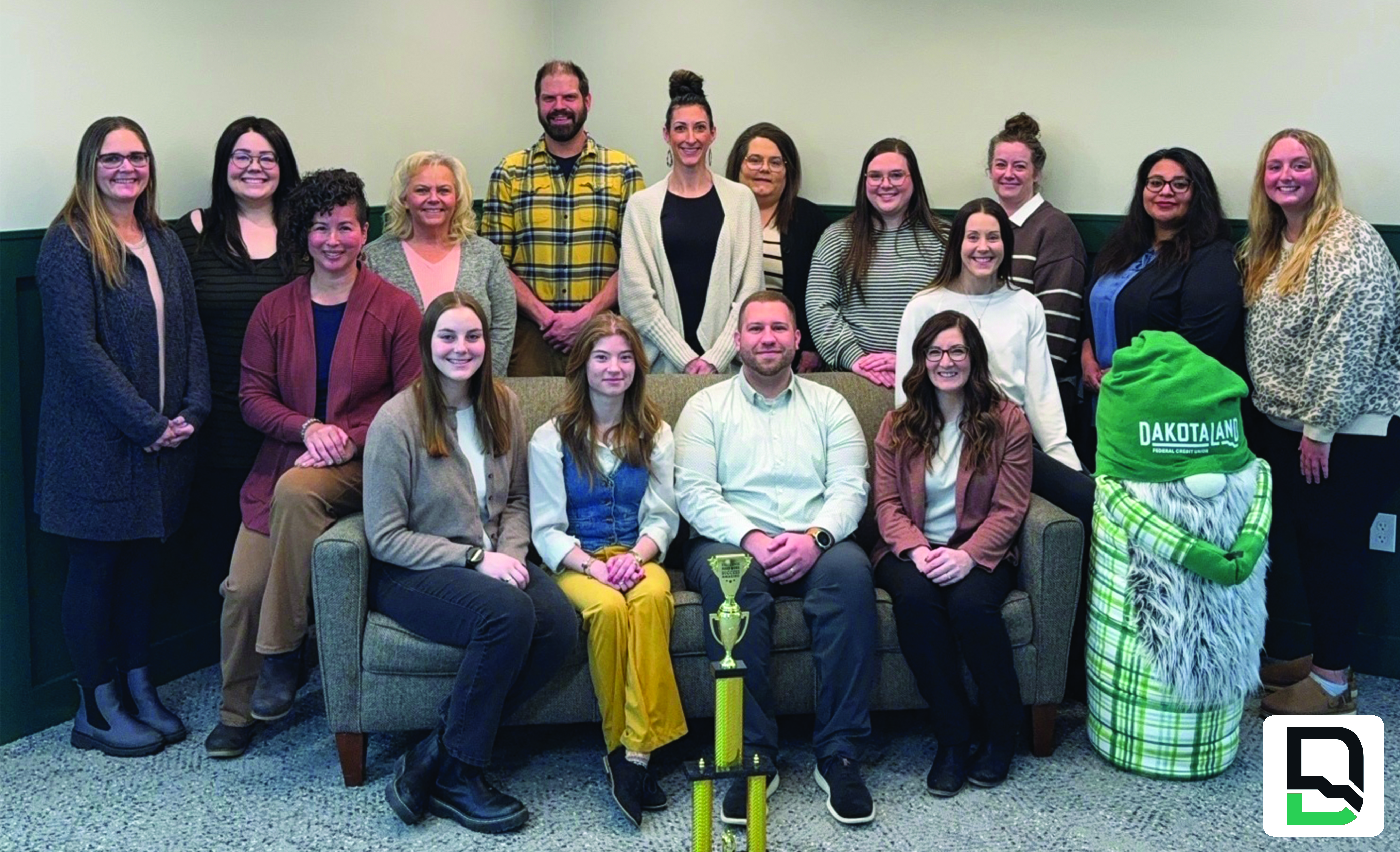 Brookings branch employees sitting in lobby with Branch of the Year trophy