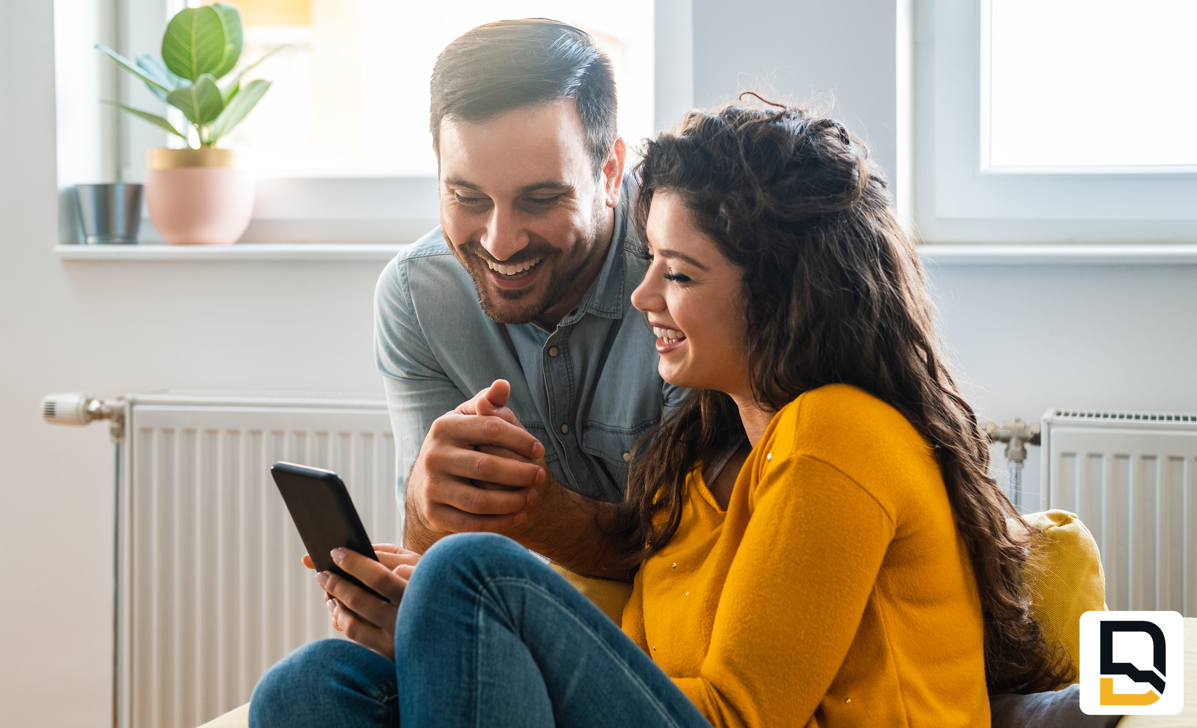 Happy couple sitting inside looking at cell phone