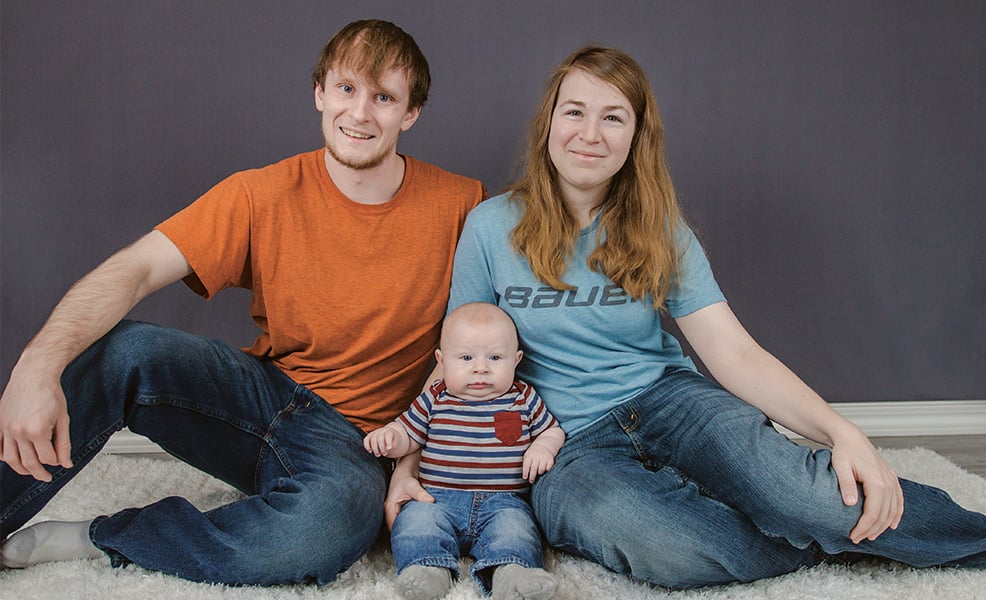 Family of three sitting in front of gray background