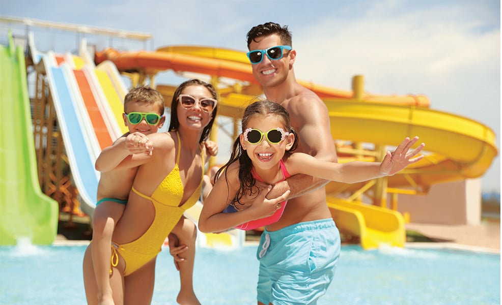 Smiling family of four wearing sunglasses at the water park