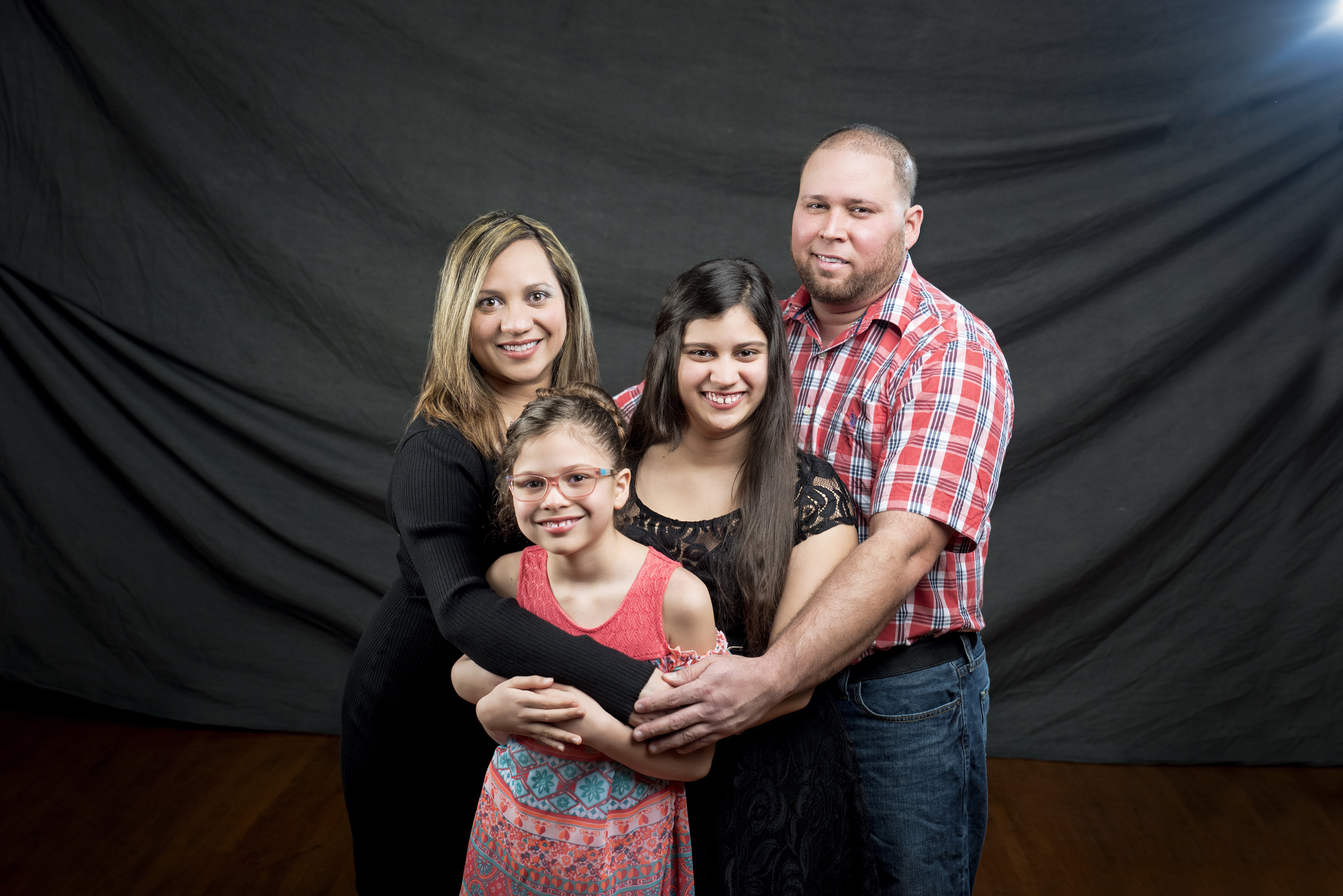The Morales-Cordero Family in photo studio with a dark gray backdrop