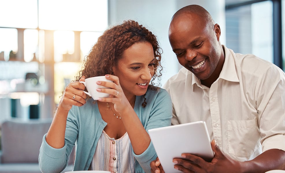 Happy African American couple having coffee while looking at tablet