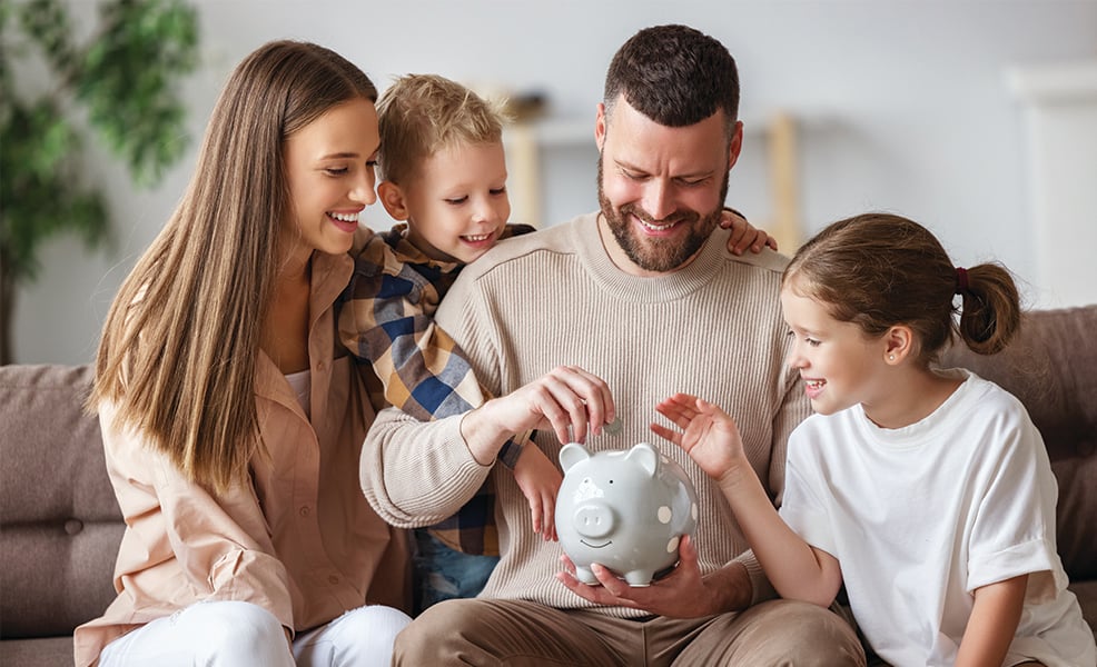 Family adding coins to piggy bank