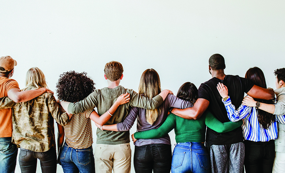 The backside of a group of people with their arms around each other in front of a white background